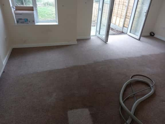 This is a photo of an empty living room with a brown carpet that is in the process of having its carpets steam cleaned works carried out by Mill Hill Carpet Cleaning.